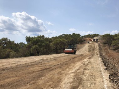 Titreşimli silindir bir yol yüzeyinin toprağını sıkıştırır. Highland Ormanı Yolu 'nun toprak işleri. Farklı makine türleri