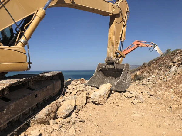 Bagger bewegen Felsbrocken bei Straßenbau auf felsigem Boden — Stockfoto