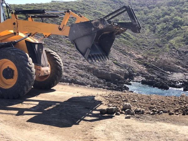 Backhoe caricatore giallo sta progettando un manto stradale durante i lavori di costruzione di strade. Movimento terra, scavi, scavi — Foto Stock