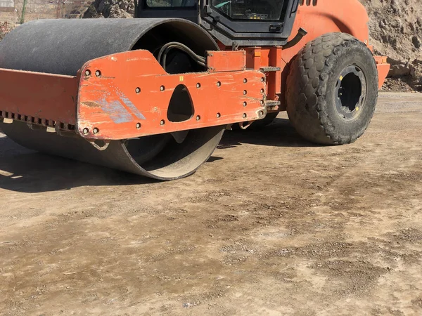 O rolo vibratório comprime o solo de uma superfície de estrada durante as obras de construção de estradas — Fotografia de Stock