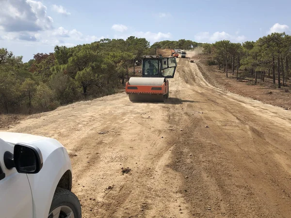 Titreşimli silindir bir yol yüzeyinin toprağını sıkıştırır. Highland Ormanı Yolu 'nun toprak işleri. Farklı makine türleri