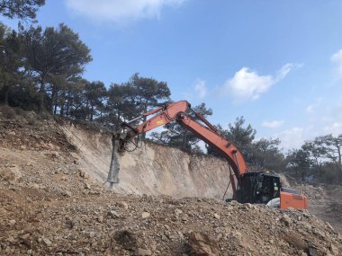 Hidroçekiç, kayalık topraklarda yol yapımı sırasında kayaları eziyor. Toprak hareketinde ağır makineler