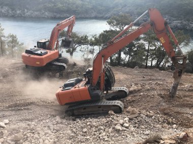 Hidroçekiç, kayalık topraklarda yol yapımı sırasında kayaları eziyor. Toprak hareketinde ağır makineler