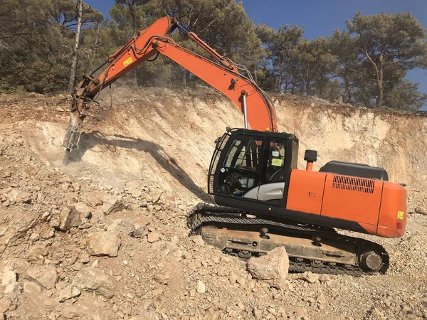 Hydrohammer está esmagando rochas durante obras de construção de estradas nos solos rochosos. Máquinas pesadas em terraplanagem — Fotografia de Stock