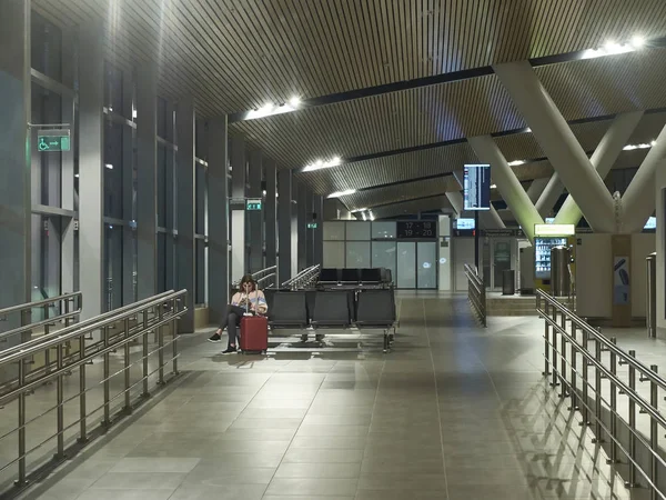 Mulher com mala vermelha está sentada no lounge do aeroporto vazio . — Fotografia de Stock