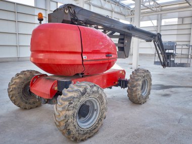 Kızıl adam inşaat alanında platform makinelerini kaldırıyor.