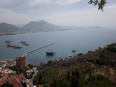 Alanya 'nın panoramik manzarası, limandaki deniz gemileri, Kizil Kule ve dağlar.