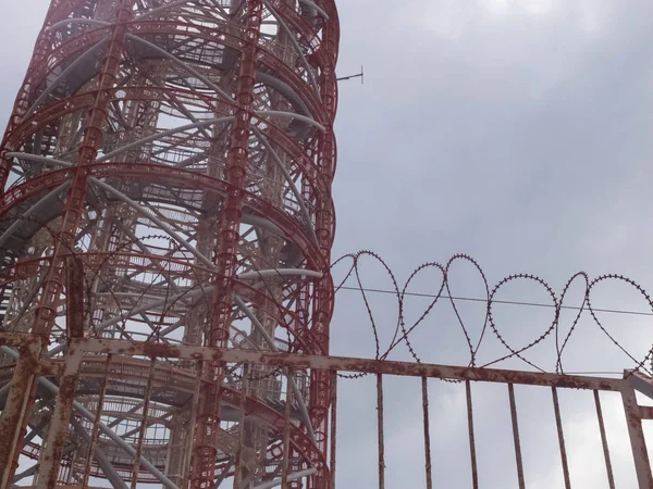Kovová radarová věž za ostnatým drátěným plotem — Stock fotografie