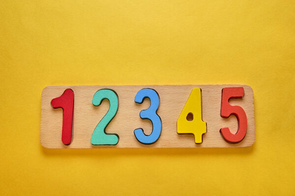 деревянные красочные цифры и доска на желтом фоне с копирайтом
