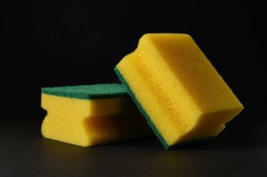 Siyah arka plana karşı iki yeni sarı sünger.