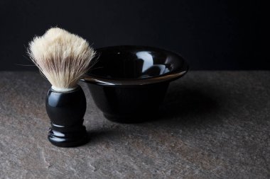Tıraş fırçası ve kase siyah arka planda taş yüzeyde
