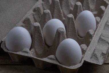 Yumurtalar yıpranmış ahşap arka planda kabın içinde.