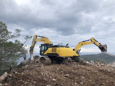 Kayalık topraklarda yol yapımı sırasında kazıcı ve hidroçekiç. Toprak taşıma, kazma ve kazı işlemlerinde ağır makineler.