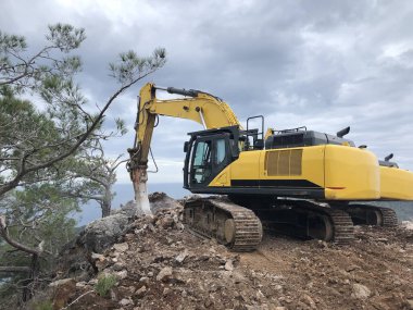 Kayalık topraklarda yol yapımı sırasında kazıcı ve hidroçekiç. Toprak taşıma, kazma ve kazı işlemlerinde ağır makineler.