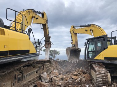 Kayalık topraklarda yol yapımı sırasında kazıcı ve hidroçekiç. Toprak taşıma, kazma ve kazı işlemlerinde ağır makineler.