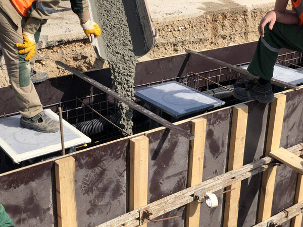 Construction workers are pooring concrete to formwork.