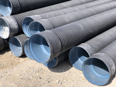 Açık hava deposuna yığılmış pvc-borular. Drenaj, tesisat, fırtına suyu ekipmanları..