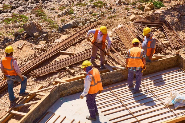 İşçiler inşaat alanında beton takviyeli temel plakası inşa ediyorlar..