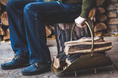 adam güdük üzerinde oturuyor ve woodpile yakacak odun tutar