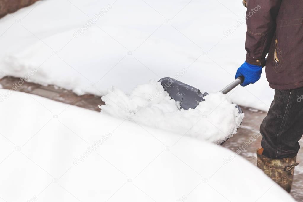 snow removal. man cleans snow from yard plastic shovel