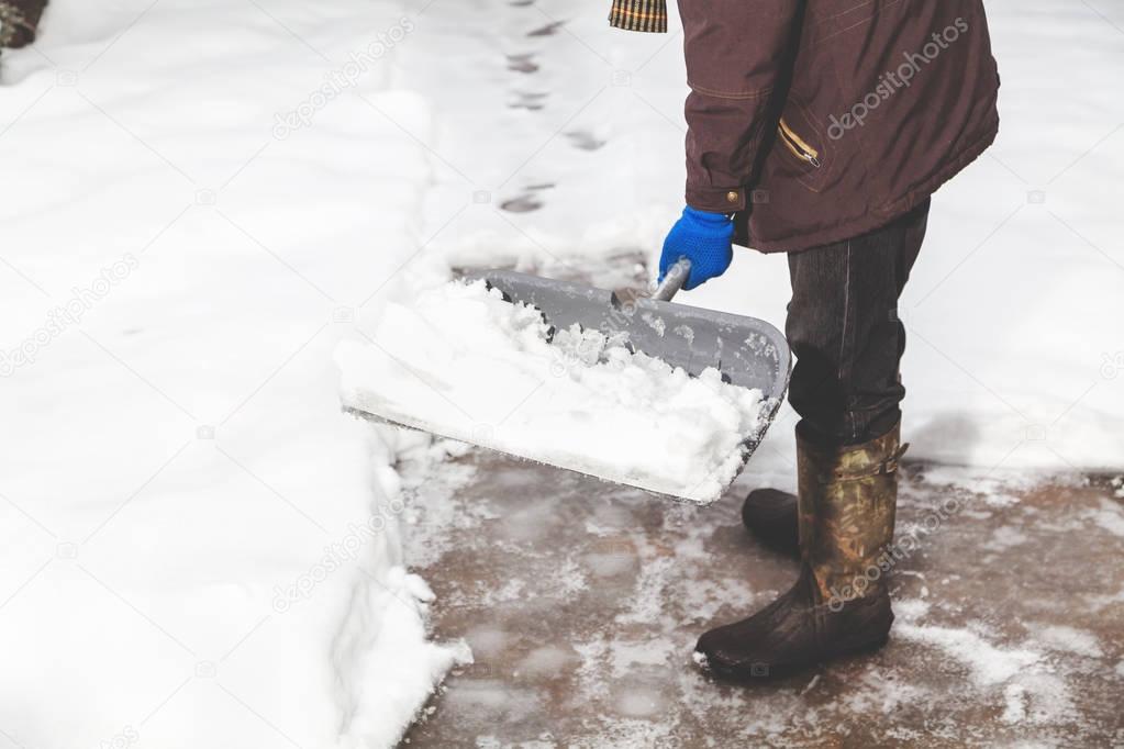 snow removal. man cleans snow from yard plastic shovel