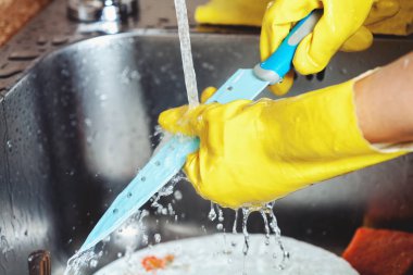 Sarı lastik eldiven elinde büyük Peynir bıçağını yıkama