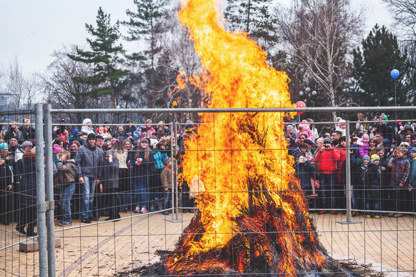 Large bonfire behind fence on Russian holiday carnival Maslenitsa