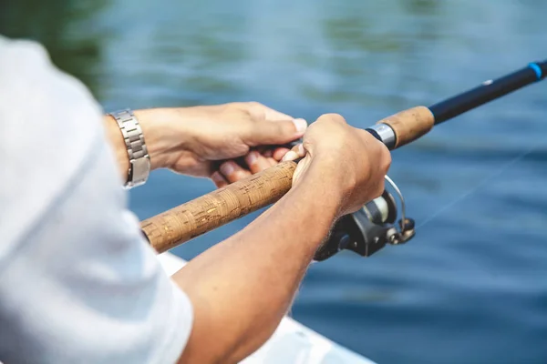 Hands fisherman holding fishing rod and reel handle is rotated — Stock Photo, Image