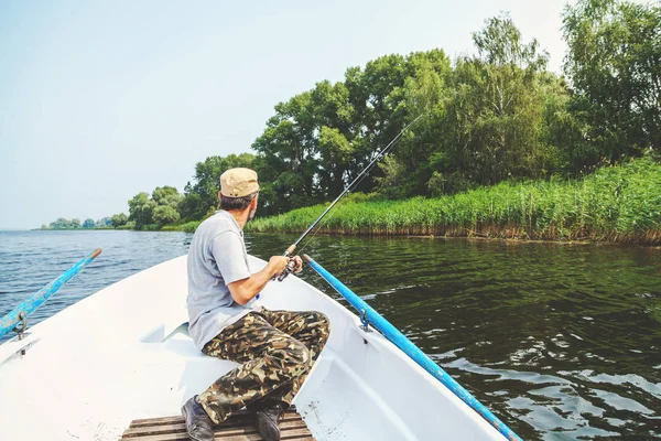 Pescador con barba sentado en barco y sosteniendo caña de pescar —  Fotos de Stock