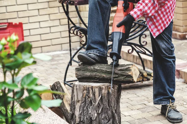 Hombre en camisa a cuadros aserrado pieza de madera en muñón — Foto de Stock