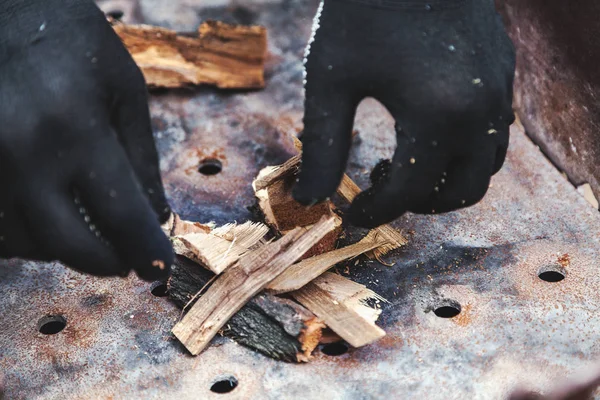Руки в перчатках лежали деревянные щепки, чтобы зажечь огонь — стоковое фото