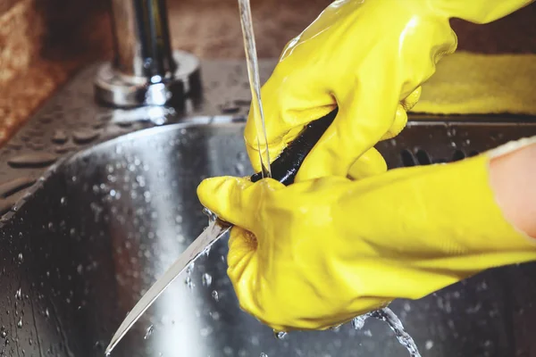 Manos en guantes de goma amarillos, lavar cuchillo pequeño — Foto de Stock