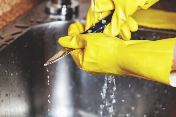 Manos en guantes de goma amarillos, lavar cuchillo pequeño — Foto de Stock