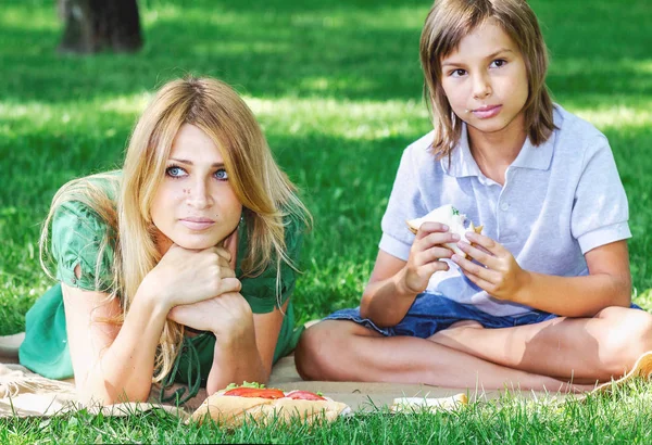 Familienfrühstück auf Gras. Mutter und Sohn essen Sandwich — Stockfoto