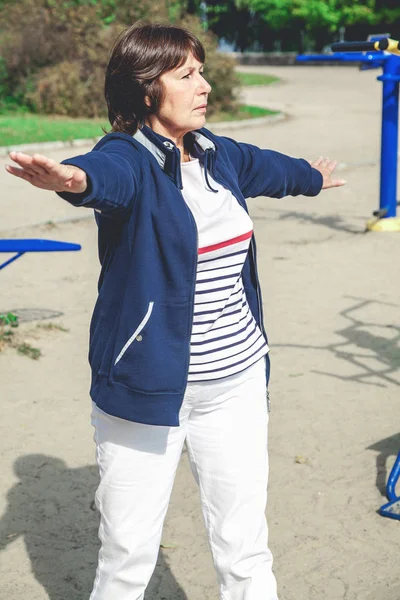 Şirin emekli kadın jimnastik egzersizleri Caddesi üzerinde gerçekleştirir.