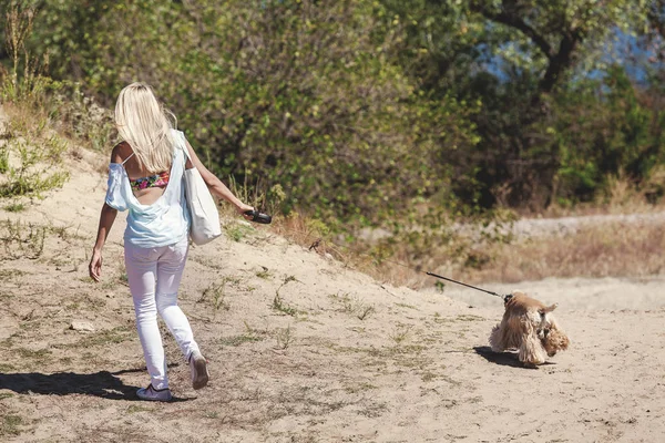 Rubia delgada paseando con un perro — Foto de Stock