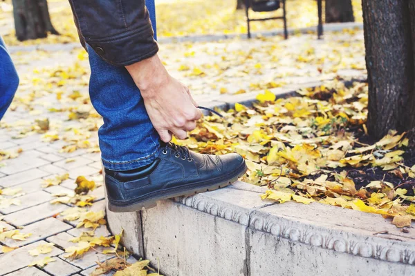 Hombre atando cordones en el parque de otoño — Foto de Stock