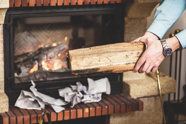 Mãos de homem segurando pedaço de madeira na lareira da frente — Fotografia de Stock