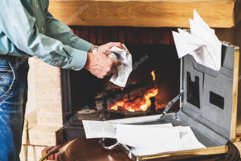 Businessman destroying important documents from case in fireplac