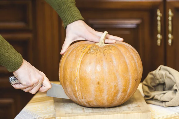 stock image Hands of man cut ripe pumpkin with big knife