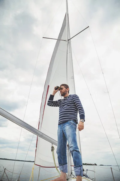 Capitano in camicia a righe guardando attraverso binocoli vela yach — Foto Stock