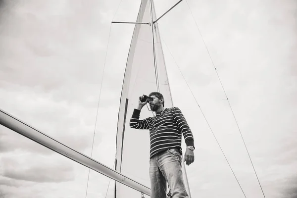 Monochromatický kapitán v pruhované košili při pohledu přes dalekohled s — Stock fotografie