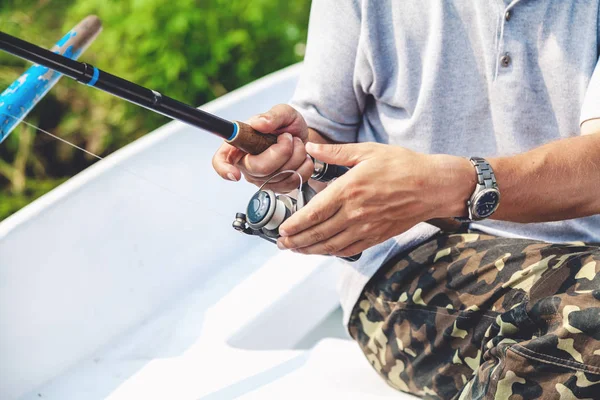 Die Hände des Fischers, der Angelrute und Spulengriff hält, werden gedreht — Stockfoto