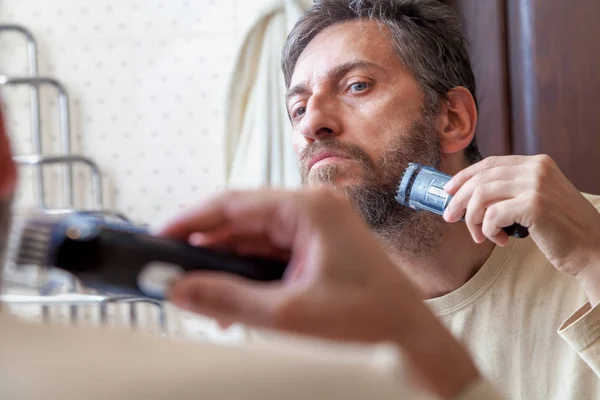 Grooming beard. Man alone shears beard in bathroom — Stock Photo, Image