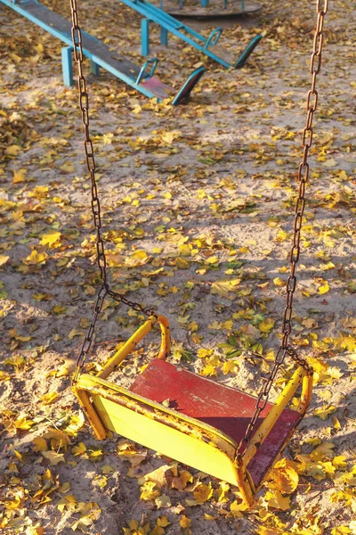 Empty children's swing in fall site — Stock Photo, Image