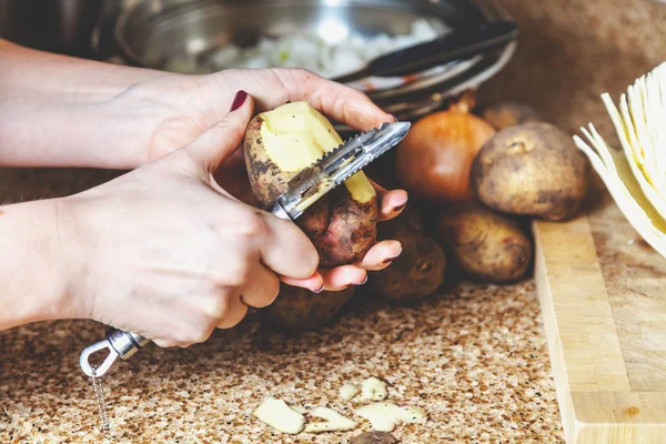 Het reinigen van aardappelen. Handen vrouw schoon aardappelen met speciale voldaan — Stockfoto