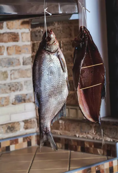 İki büyük füme balık tuğla duvar arka plan üzerinde asılı