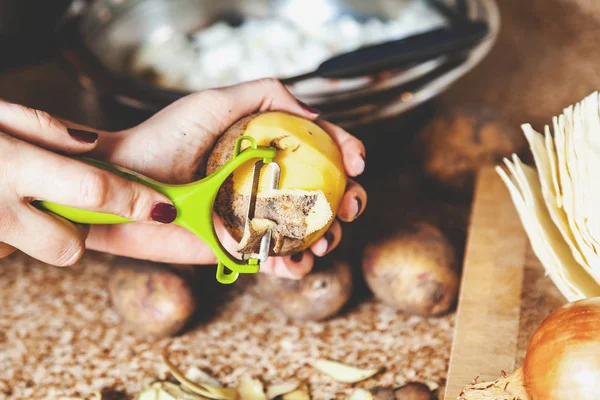 Cleaning potatoes. Woman's hands clean potatoes special tool — Stock Photo, Image