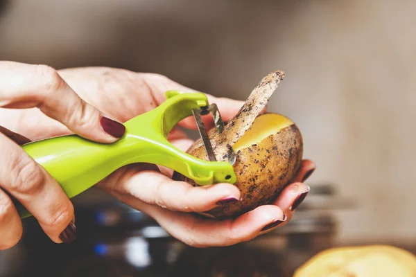 Cleaning  potatoes. hands of woman clean potatoes with special t — Stock Photo, Image