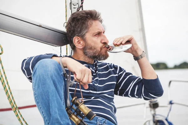 Hombre con barba se sienta en las bebidas del yate del frasco — Foto de Stock